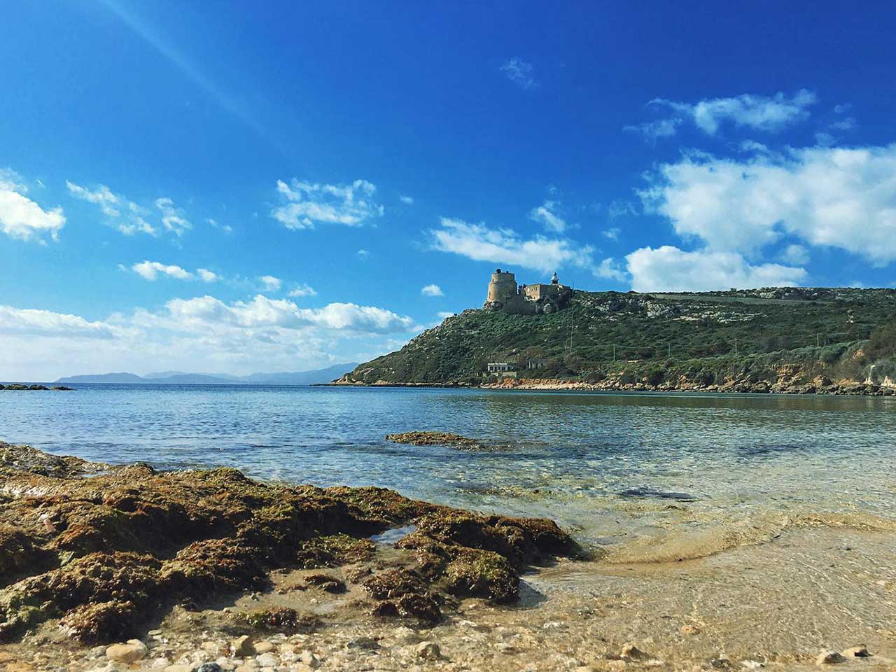 La plage de Calamosca avec la tour espagnole sur le promontoire au fond