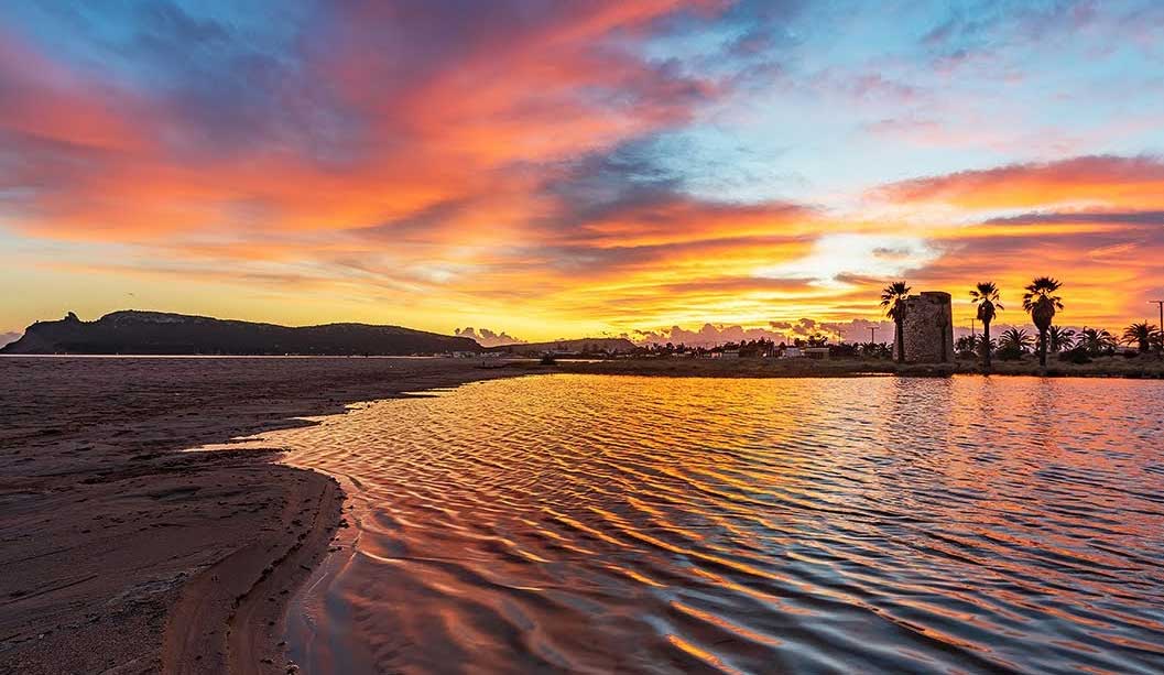 Le coucher de soleil sur le Poetto, avec la tour et les palmiers à contre-jour