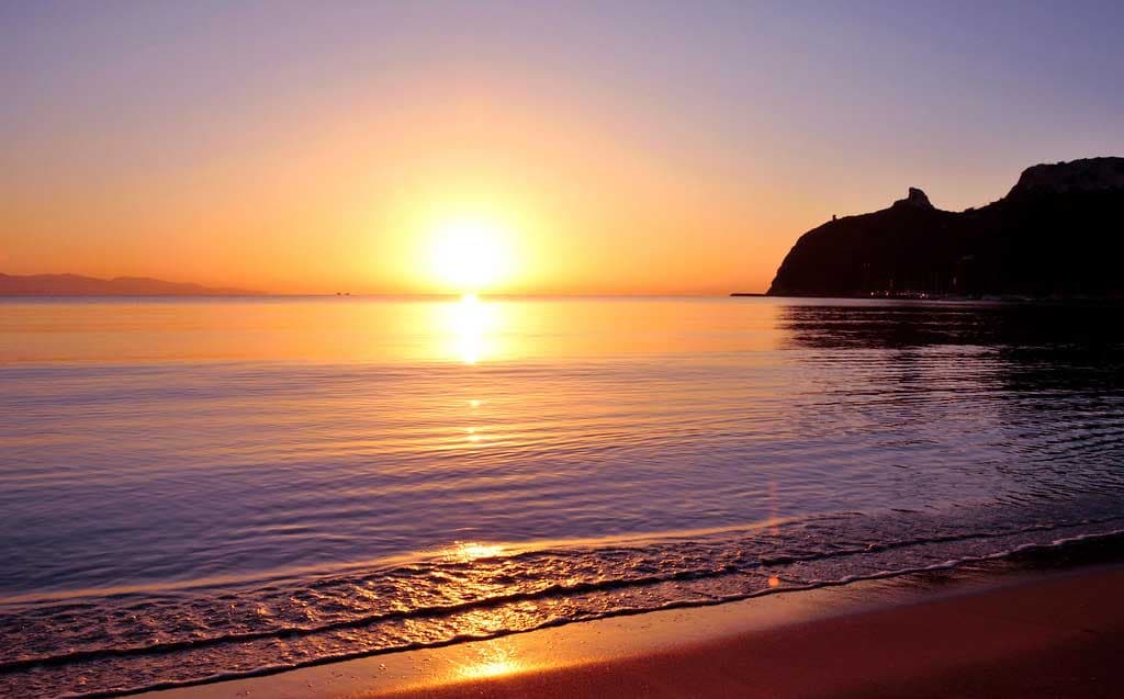 Le soleil descendant sur la mer devant le Poetto, avec la Sella del Diavolo à contre-jour